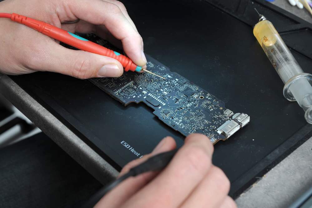 Technicien en intervention de microsoudure sur carte mere a l'atelier